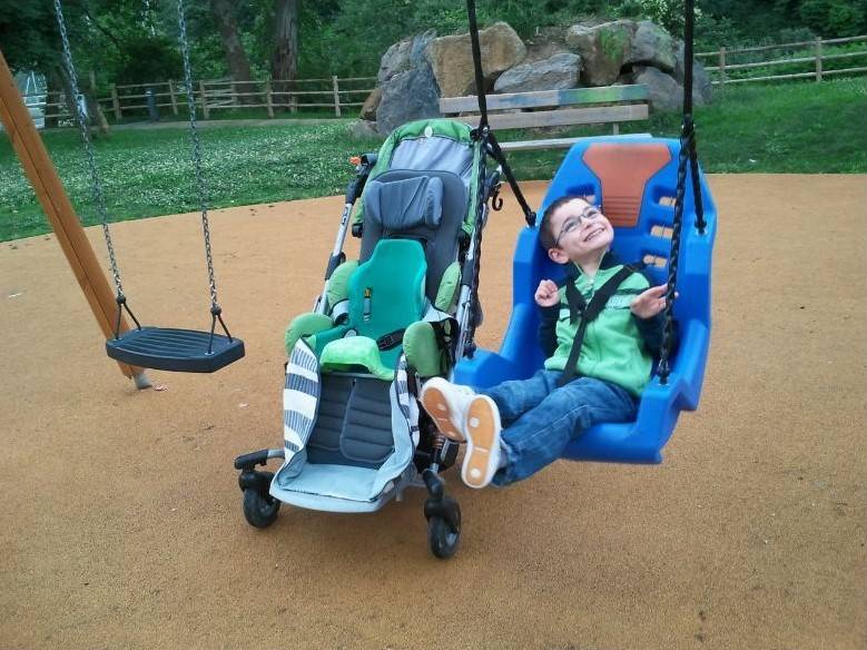 un enfant handicapé moteur se balance dans une balançoire adaptée
